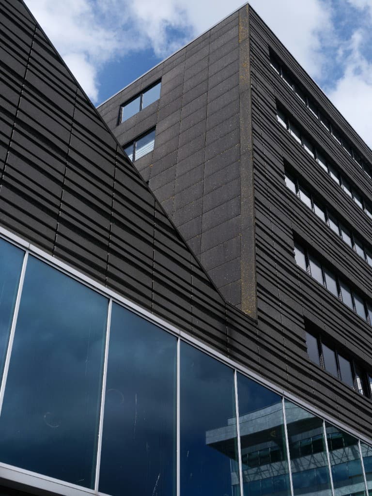 Dark ribbed ACP facade with recessed glazing