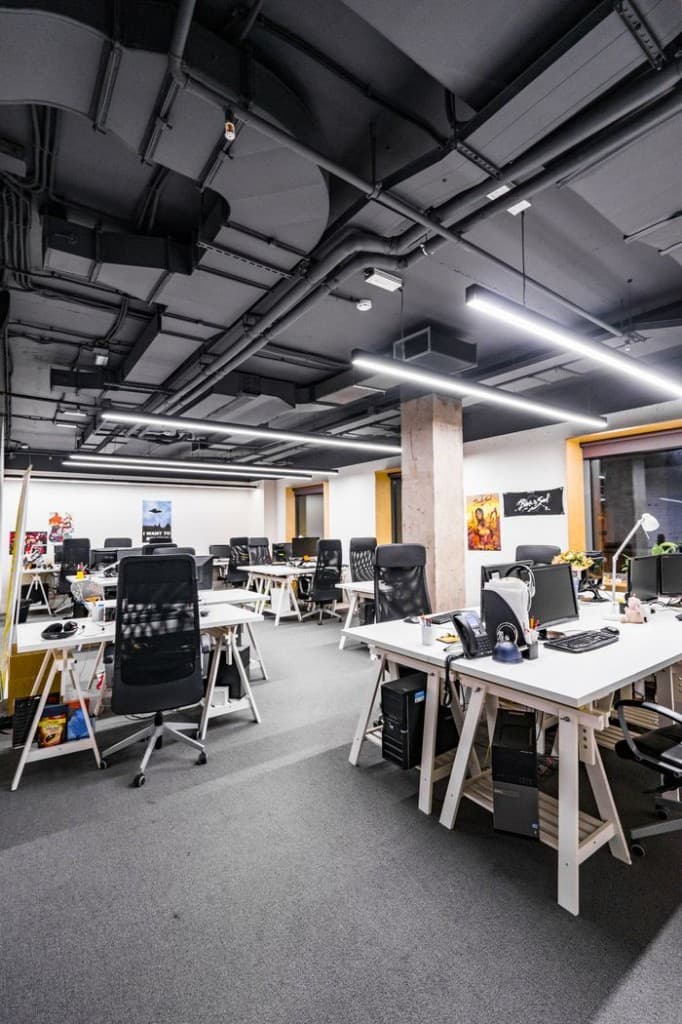 Industrial studio floor with white desks and charcoal ceiling